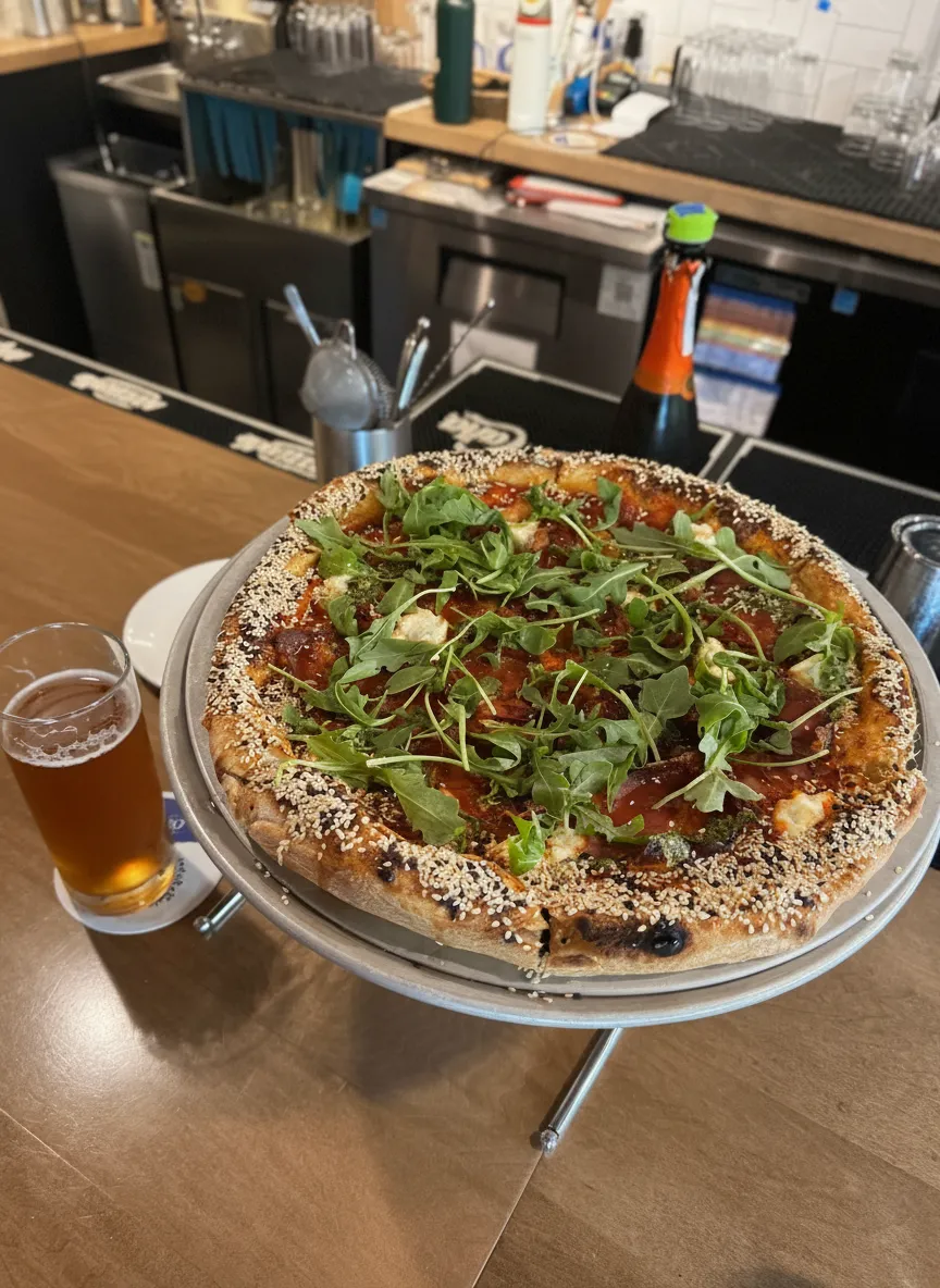 Pizza with arugula and sesame crust, and a beer